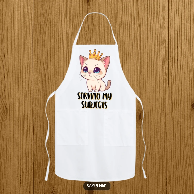 Funny Siamese cat wearing a miniature crown, looking regal while perhaps supervising cooking on a colorful apron, a humorous kitchen accessory.