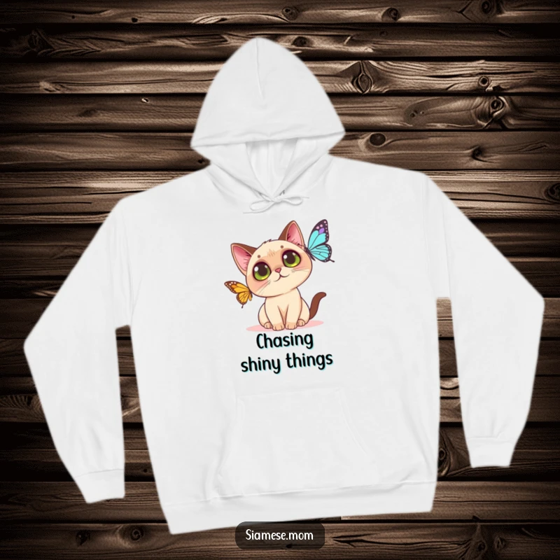 Funny Kawaii Siamese cat hoodie illustration of a curious cat with large eyes playfully swatting at a colorful butterfly.
