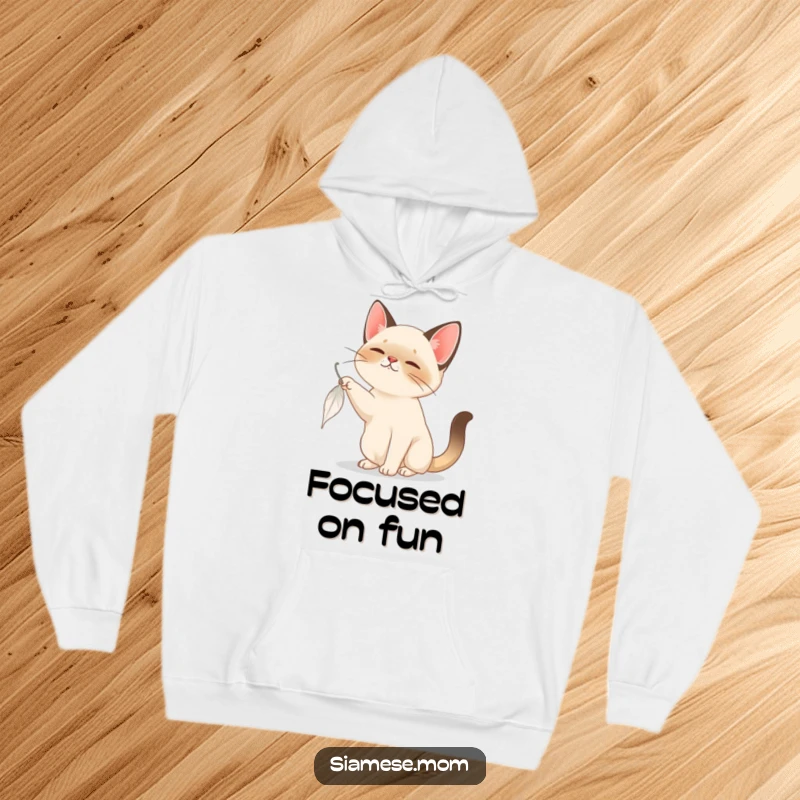 Funny Siamese Cat Hoodie: A soft Siamese cat is captured in the act of playfully batting a falling feather, exuding joy.