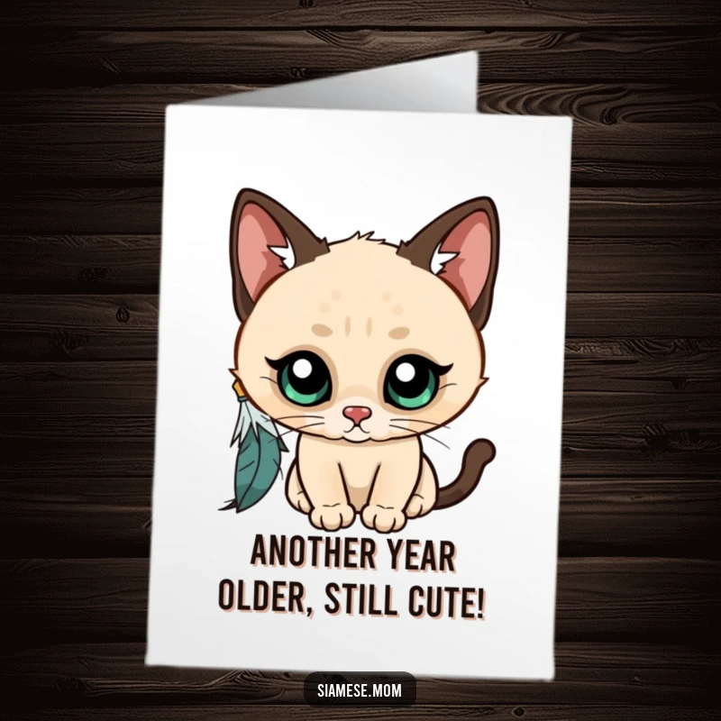 Funny Free Printable Birthday Card: Kawaii Siamese cat with wide eyes playfully bats at a feather, full of curiosity and mischief.