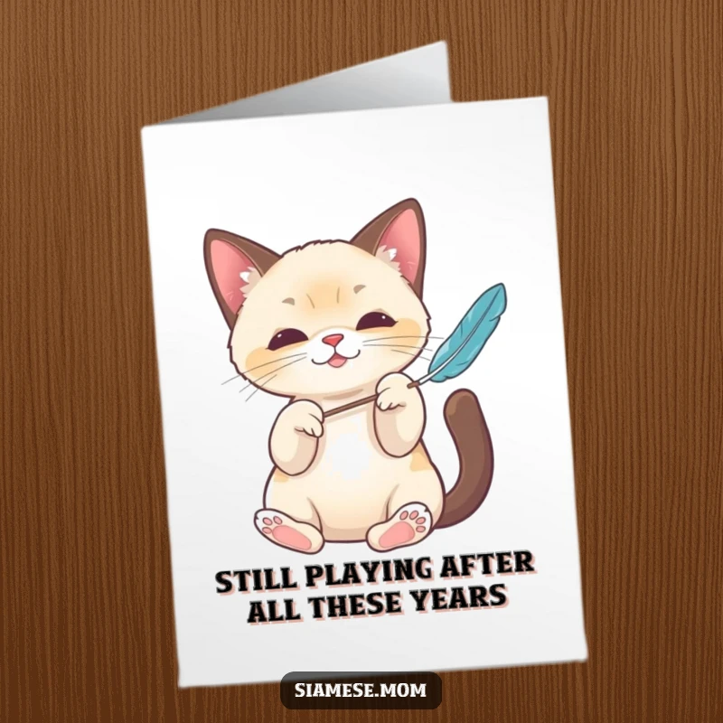 Funny Free Printable Birthday Card: Energetic Kawaii Siamese Cat playfully batting a feather toy with cute paws.